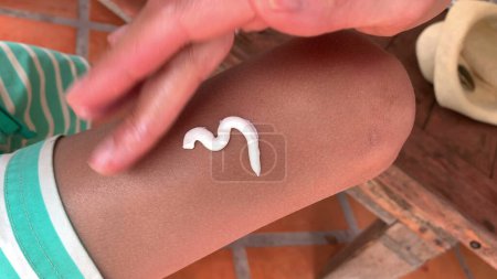 Photo for Child applying and rubbing sunblock lotion to skin, healthy prevention - Royalty Free Image