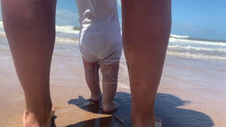Téléchargez les photos : Bébé bébé premiers pas à la plage pieds nus - en image libre de droit