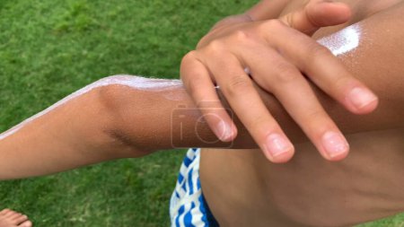Téléchargez les photos : Crème solaire pour enfants frottant à l'extérieur. Jeune garçon appliquant crème solaire - en image libre de droit