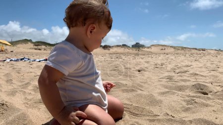 Foto de Bebé en la playa poniendo arena en la boca - Imagen libre de derechos