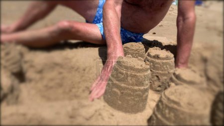 Téléchargez les photos : Senior homme appréciant la retraite à la plage bâtiment Sandcastle - en image libre de droit