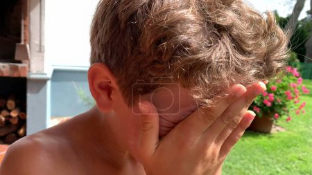 Téléchargez les photos : Jeune garçon appliquant de la crème solaire sur le visage pendant la journée d'été - en image libre de droit
