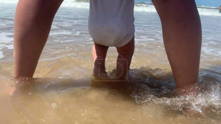 Téléchargez les photos : Bébé mignon à la plage jouant avec l'eau - en image libre de droit