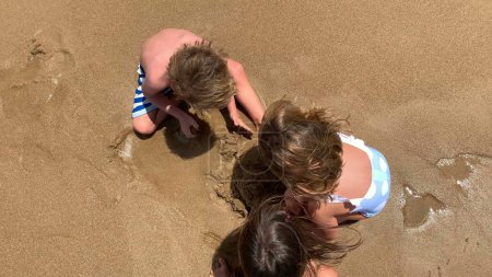 Foto de Niños en la playa jugando con arena, niños vistos desde arriba en la orilla del mar - Imagen libre de derechos