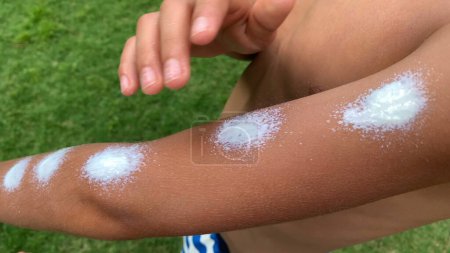 Photo for Child rubbing sun cream lotion outdoors. Young boy applying sunscreen - Royalty Free Image