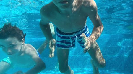 Téléchargez les photos : Enfants nageant sous l'eau à la piscine. Des enfants actifs qui s'amusent. Deux garçons nagent - en image libre de droit