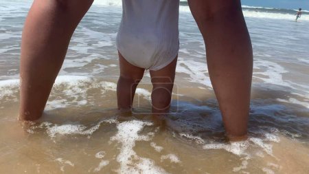 Téléchargez les photos : Bébé pieds et orteils à la plage sensation d'eau de vague. Mer vague s'écrase - en image libre de droit