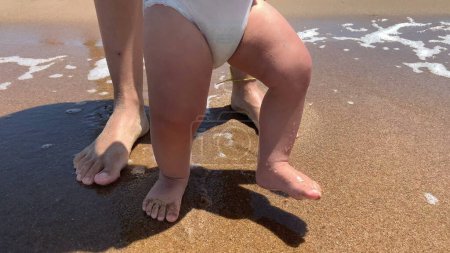 Photo for Infant baby feet walking at beach sand, wave come crashing - Royalty Free Image