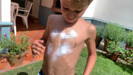 Photo for Child rubbing sunblock lotion into body chest. Young boy applying sunscreen protection - Royalty Free Image