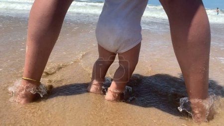 Foto de Lindo bebé en playa orilla jugando con agua - Imagen libre de derechos