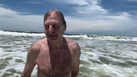 Téléchargez les photos : Older man at beach enjoying water. Senior retired person bathing at sea - en image libre de droit