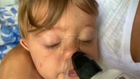 Téléchargez les photos : Mère décongestionnant le mucus de bébé avec de l'eau salée salée, enlevant le mucus du bébé pleurant - en image libre de droit