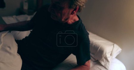 Photo for Older man lying down in bed at night turning off nightstand lamp light OFF, person going to sleep - Royalty Free Image