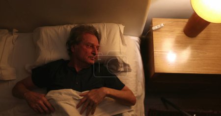 Photo for Person suffering from insomnia, old man unable to sleep, wakes in the middle of the night - Royalty Free Image