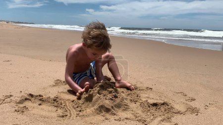 Foto de Niño jugando con arena en la playa en vacaciones de verano - Imagen libre de derechos