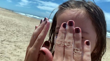Téléchargez les photos : Mère appliquant de la crème solaire à son enfant fille - en image libre de droit
