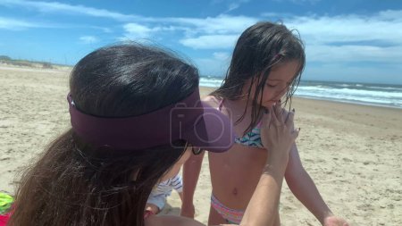 Téléchargez les photos : Mère appliquant de la crème solaire à sa petite fille - en image libre de droit