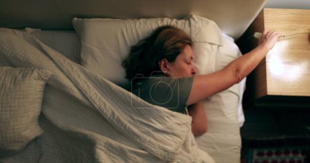 Photo for Senior woman resting in bed turning light off - Royalty Free Image