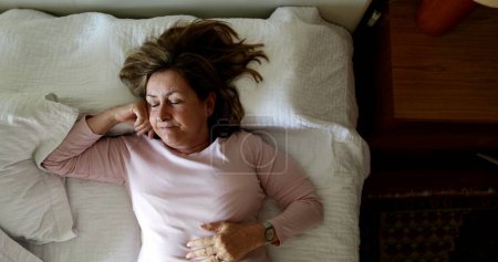 Téléchargez les photos : Older woman getting up from bed. person gets up from nap - en image libre de droit