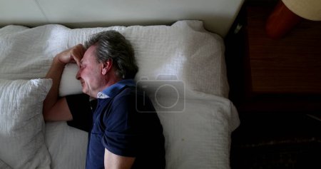 Photo for Older man resting in bed during afternoon nap - Royalty Free Image