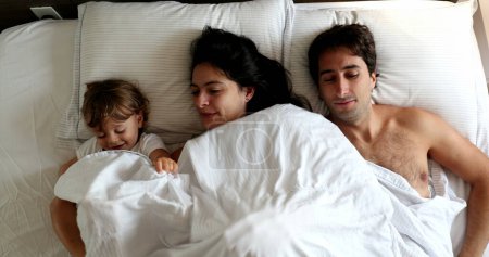 Foto de Family in bed in the morning, top view. mother father and baby - Imagen libre de derechos