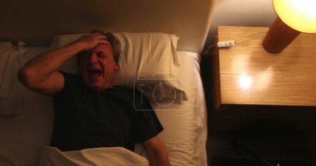 Photo for Person waking up at night, turning bedside light ON, man stretching and getting up from bed - Royalty Free Image