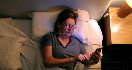 Foto de Woman going to sleep, turning nightstand light OFF - Imagen libre de derechos