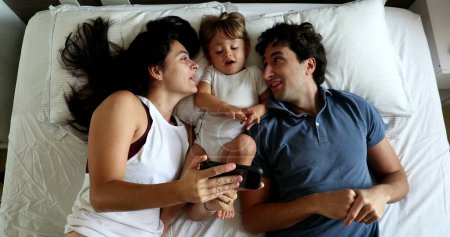 Photo for Couple in bed with infant toddler baby boy, top view - Royalty Free Image