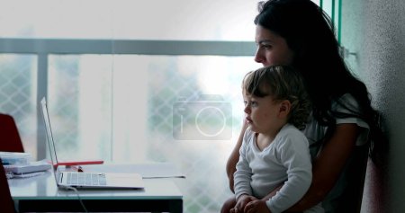 Téléchargez les photos : Mother in front of laptop with baby infant - en image libre de droit