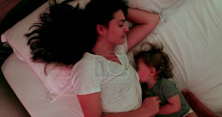 Photo for Mother breastfeeding in bed at night, top view - Royalty Free Image
