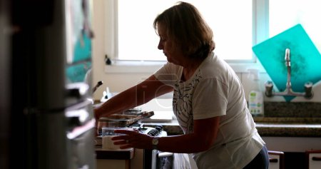 Foto de Candid older woman cooking at home, casual and real life - Imagen libre de derechos