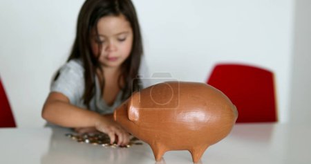 Téléchargez les photos : Little girl saving money inside piggy bank - en image libre de droit