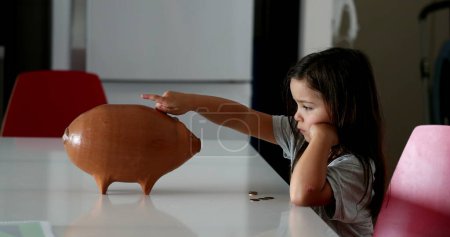 Foto de Little girl saving money inside piggy bank - Imagen libre de derechos