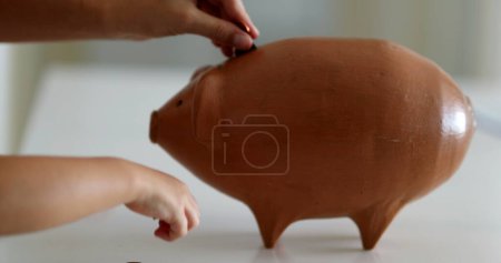 Téléchargez les photos : Close-up hands adding coins inside piggy bank investment - en image libre de droit