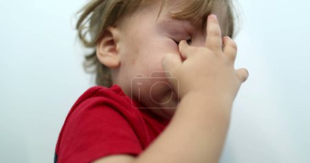 Téléchargez les photos : Tired toddler boy rubbing eye with hand. Sleepy baby child - en image libre de droit