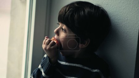 Téléchargez les photos : Jeune Absorbé dans la vue, mordre dans la fraise fraîche - en image libre de droit