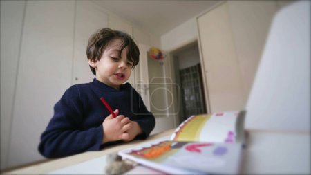Téléchargez les photos : Creative Child se prépare à dessiner, à choisir un stylo à colorier dans le tiroir du bureau, à s'asseoir dans la chambre à coucher concentrée pour faire l'étude de la maternelle à l'école - en image libre de droit