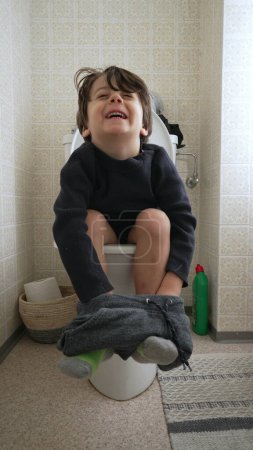 Photo for One Small Boy Sitting on Toilet in Bathroom, Childhood Potty Training Concept in Vertical Video - Royalty Free Image