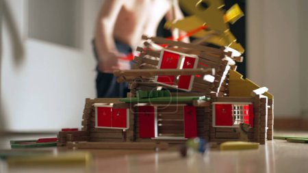 Photo for Child destroying house construction miniature. Kid kicking model wood home. Little boy boy misbehavior, educational childhood concept - Royalty Free Image