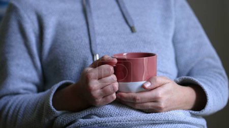 Photo for Close-up woman hand holding warm cup of tea or coffee sipping beverage in the morning, starting the day routine concept - Royalty Free Image
