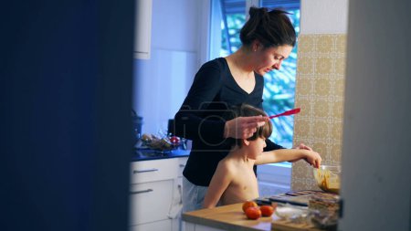 Foto de Candid madre e hijo cocinar en casa, la preparación de la comida de pastelería juntos en la vida real auténtica crianza escena doméstica - Imagen libre de derechos