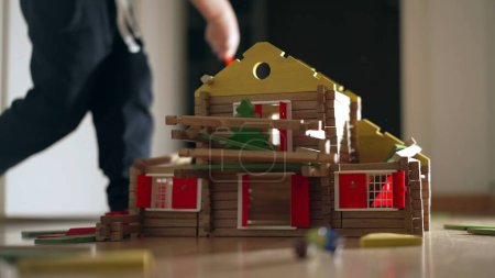 Photo for Child destroying house construction miniature. Kid kicking model wood home. Little boy boy misbehavior, educational childhood concept - Royalty Free Image