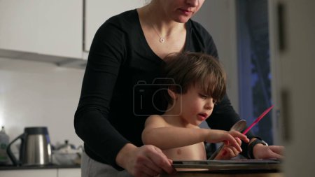 Téléchargez les photos : Mère et petit garçon préparant le dessert ensemble dans la cuisine, Scène de cuisine familiale authentique - en image libre de droit