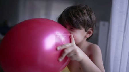 Photo for One fun child blowing up balloon with mouth. Happy small boy biting balloon with teeth - Royalty Free Image