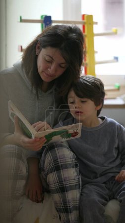 Photo for Candid Mother Telling Story to Child in Bedroom, Authentic Parenting Scene with Mom Holding Book and Little Son, Vertical Video - Royalty Free Image