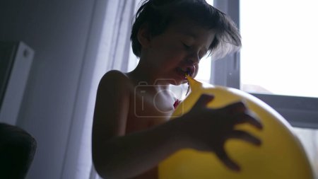 Photo for Kid biting balloon with mouth. Happy small boy deflating balloon with teeth - Royalty Free Image