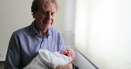 Foto de Grand-father smiling to camera while holding newborn baby - Imagen libre de derechos