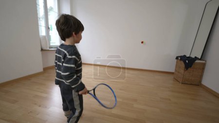 Téléchargez les photos : Tennis d'intérieur pour enfants sportif Jouez dans un appartement non meublé Chambre à coucher, concept de relocalisation de nouveau départ familial - en image libre de droit
