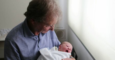 Téléchargez les photos : Nouveau-né bébé étant grand-père à côté de la fenêtre de l'hôpital - en image libre de droit