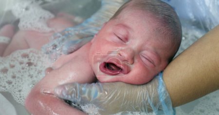 Photo for Newborn baby taking bath relaxing eyes closed feeling warm water - Royalty Free Image